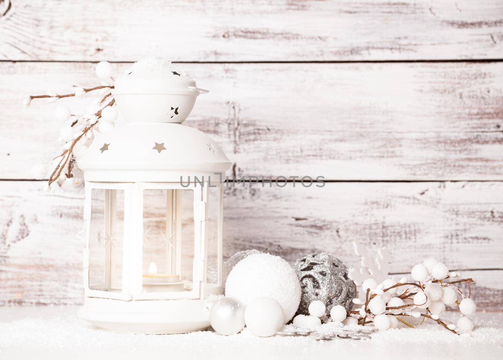 Cristmas lantern with decorations and snow over white shabby wooden background