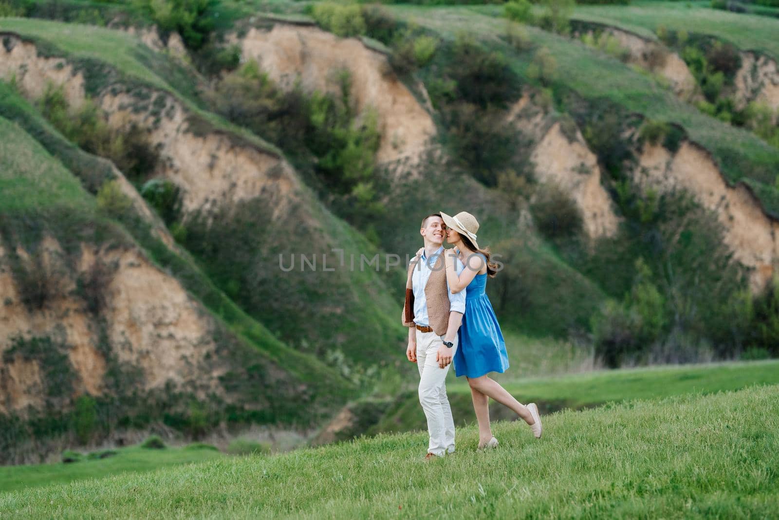 young couple a guy and a girl are walking in the green mountain hills