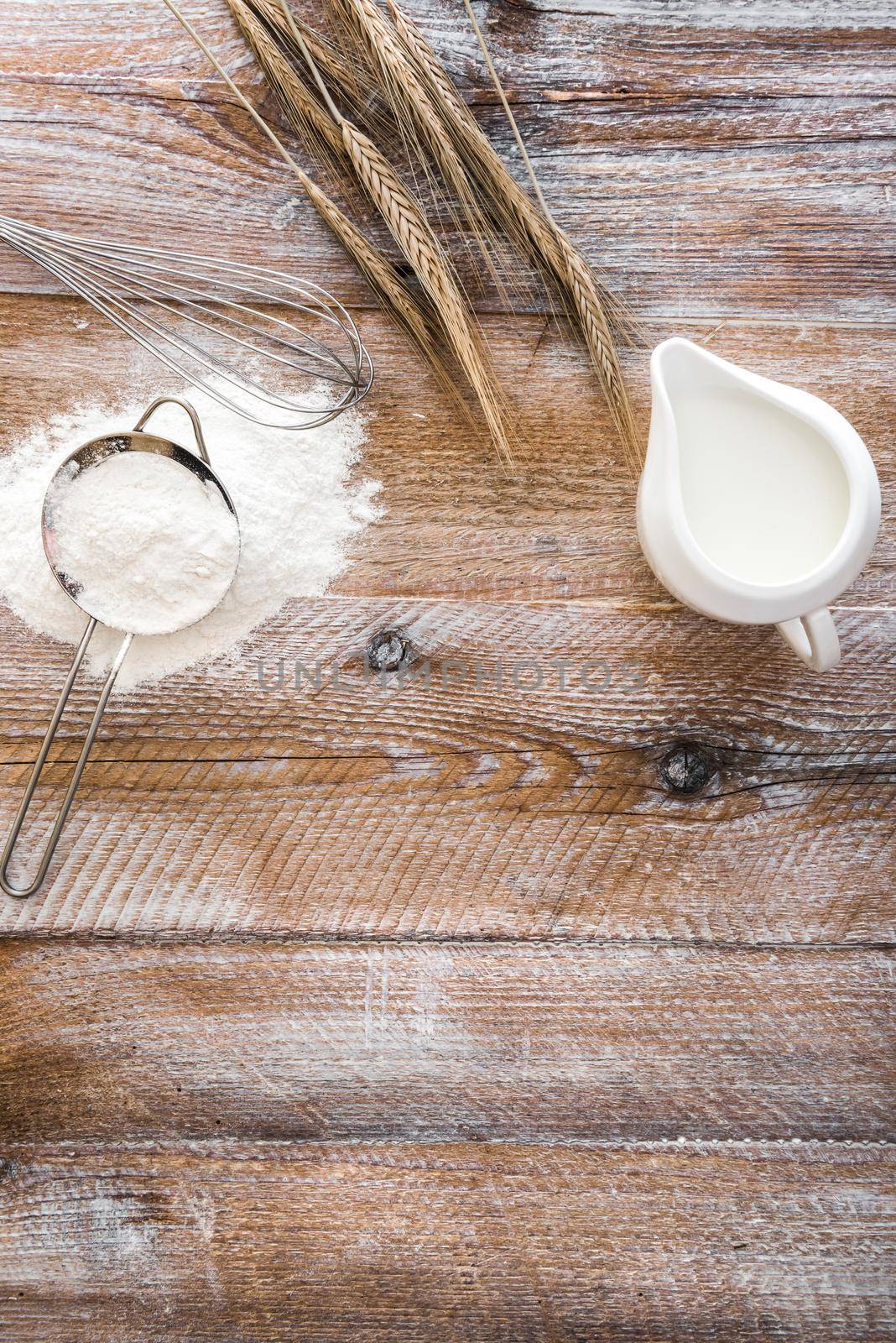 Flour sieve, wheat ears and jug on a wooden table