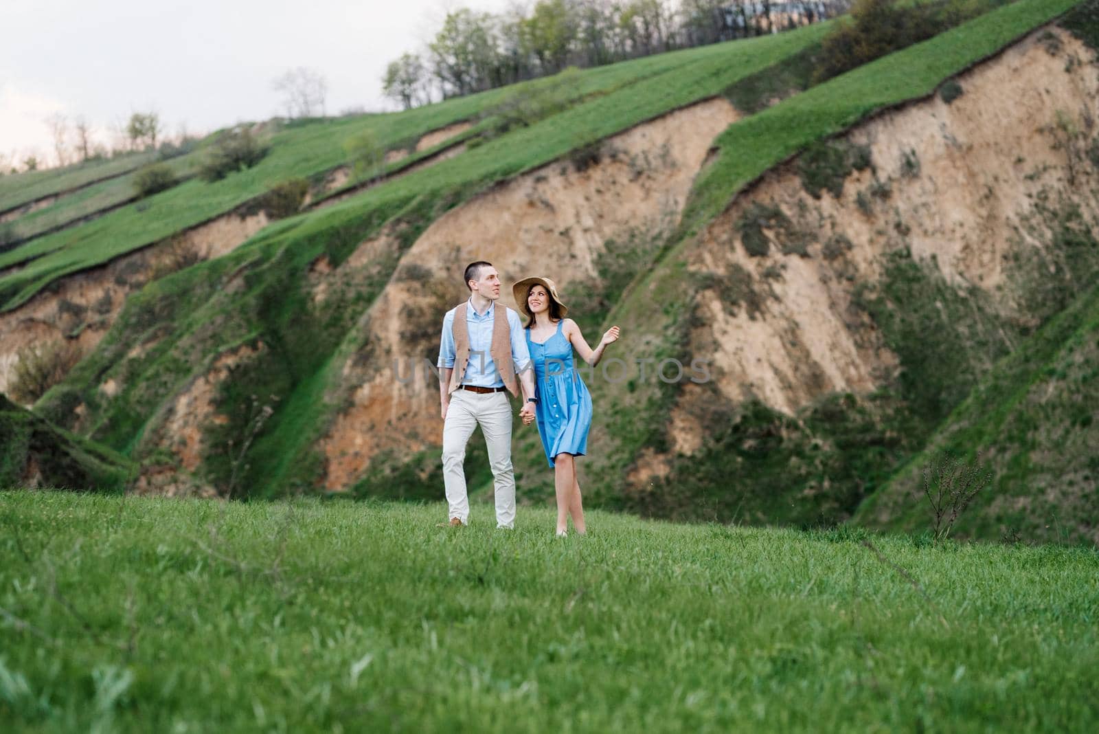 young couple a guy and a girl are walking in the green mountain hills