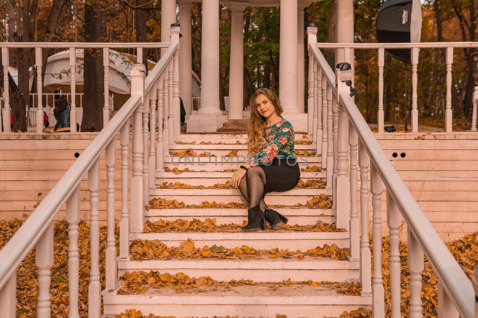 A girl sits on a white staircase in an autumn park in the woods. Beautiful blond by 89167702191