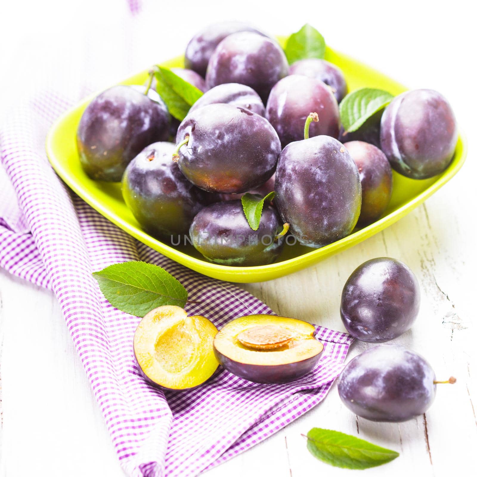 Fleshy plums in a bowl on the table