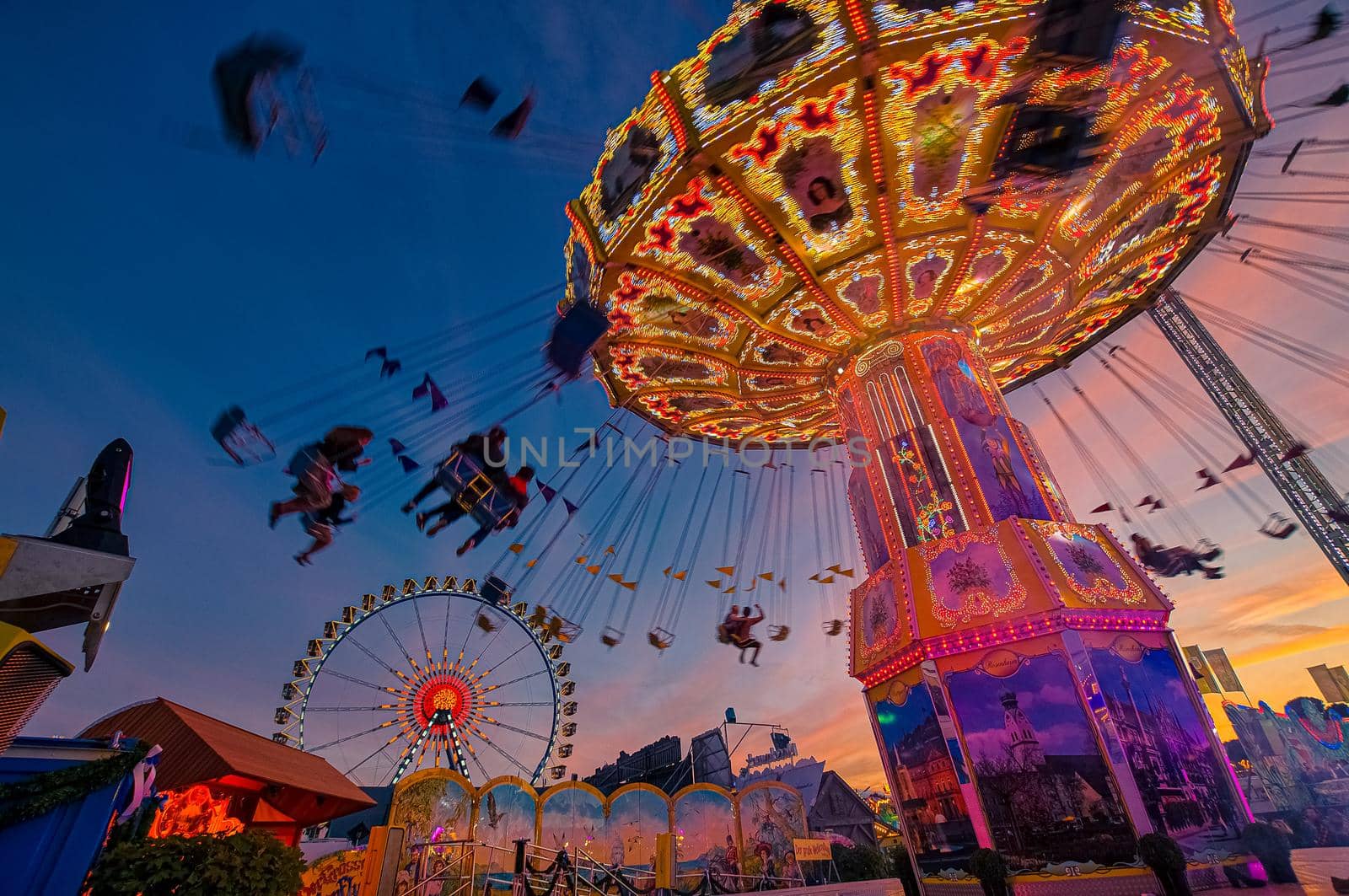 Chain carusel with silhouttes of people having fun at the Oktoberfest in Munich. by AllesSuper