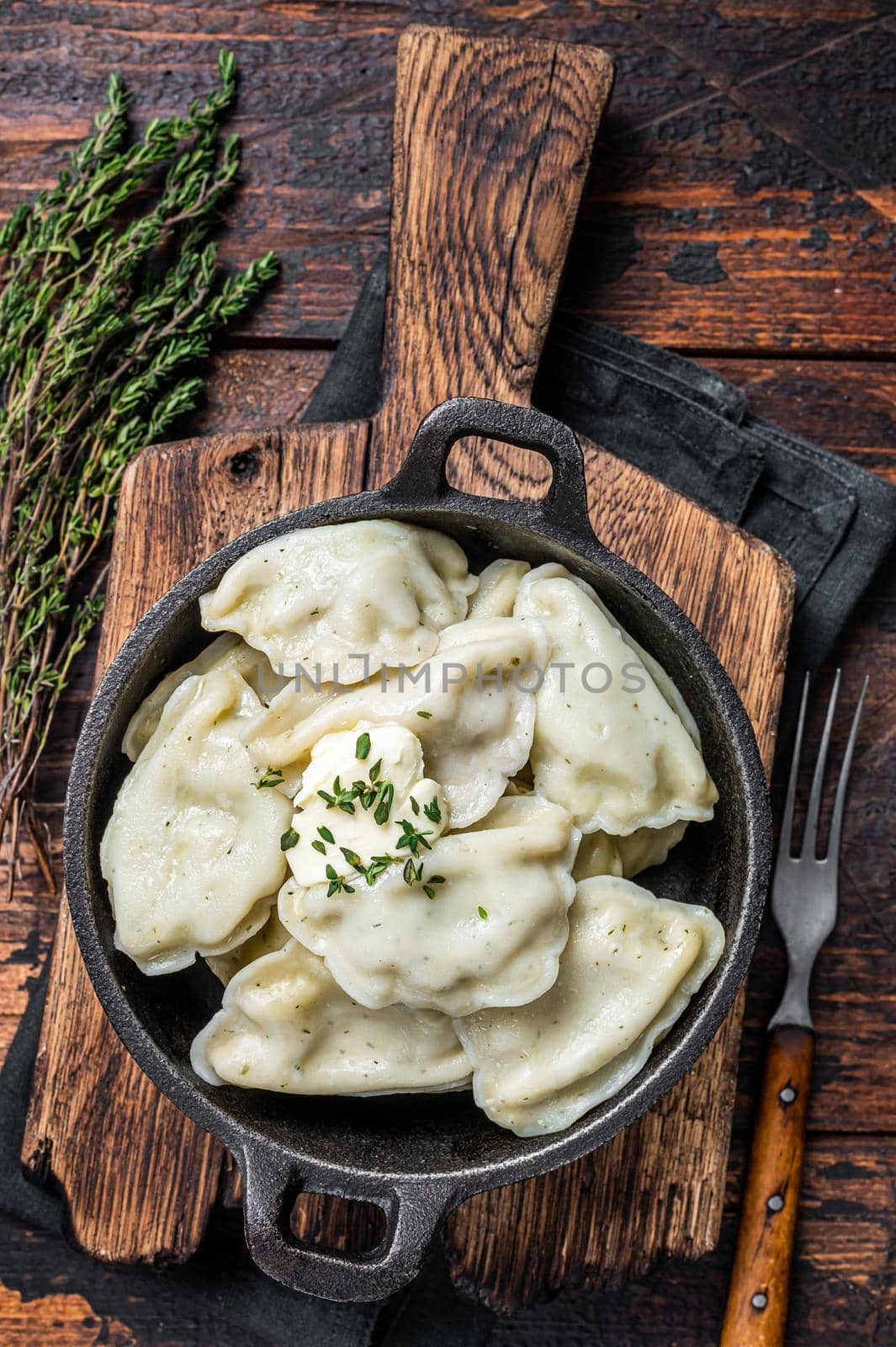 Homemade dumplings, vareniki, pierogi stuffed with potato in a pan. Dark wooden background. Top View.