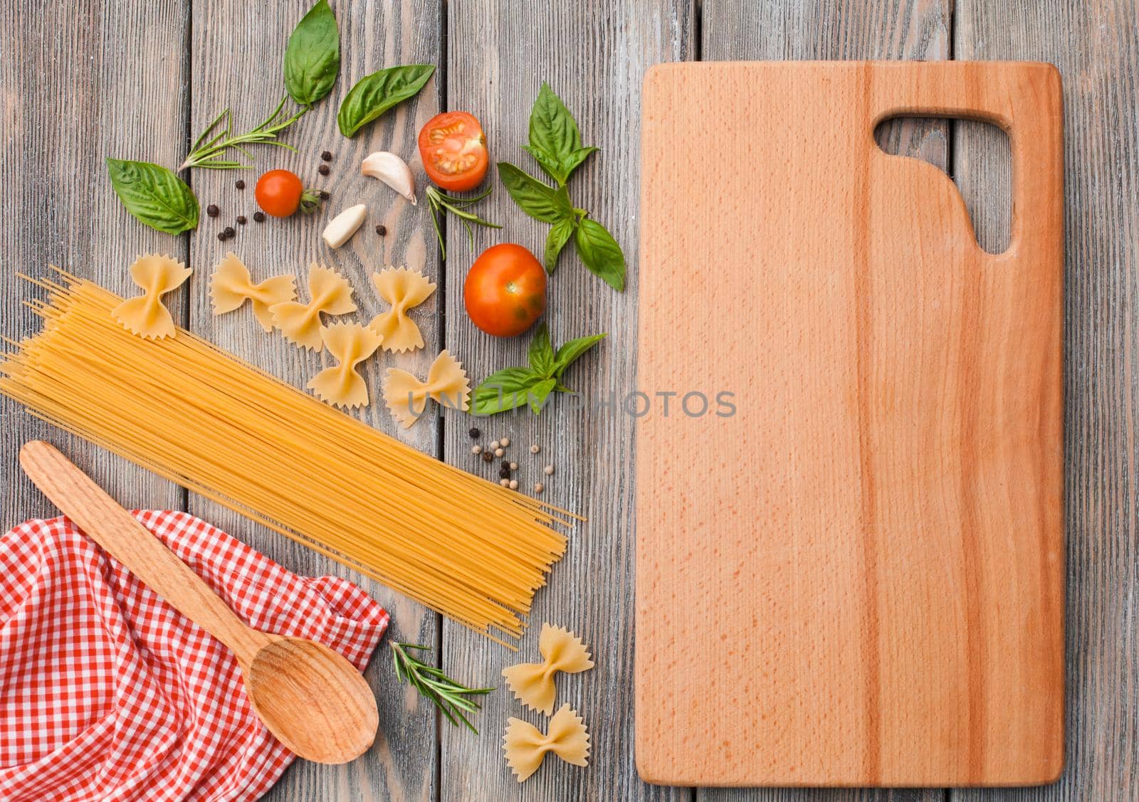 Raw Italian pasta with tomato sauce ingredients and cutting board