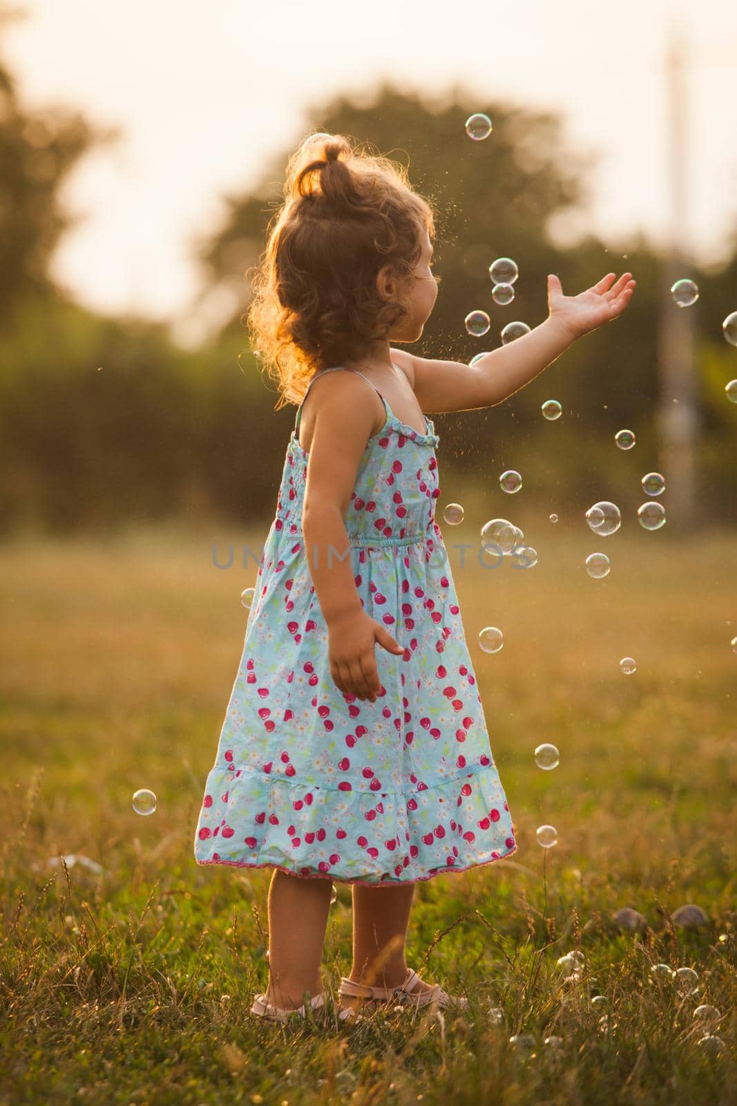 Pretty girl runs for the bubbles in the park on the sunset