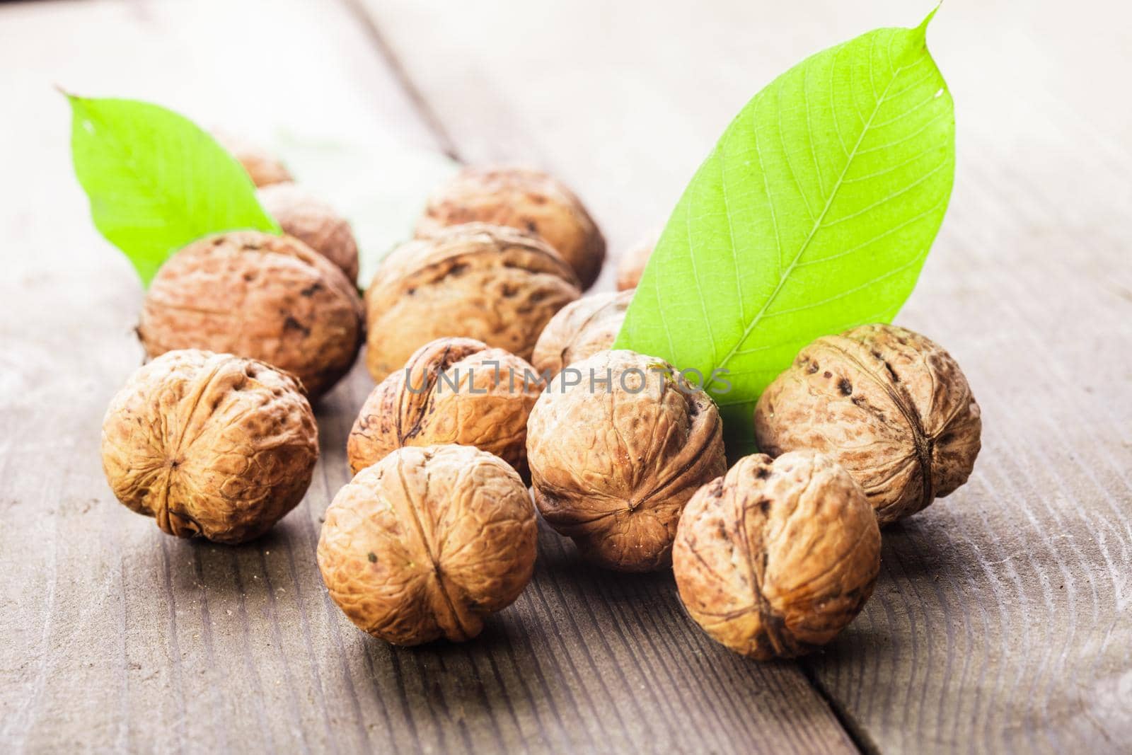 Walnuts with shell and green leaf on the wooden table