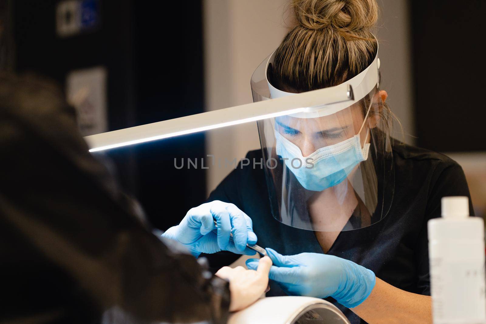 Aesthetician doing the manicure, filing the nails with a file to his client in a beauty center. Business and beauty concepts