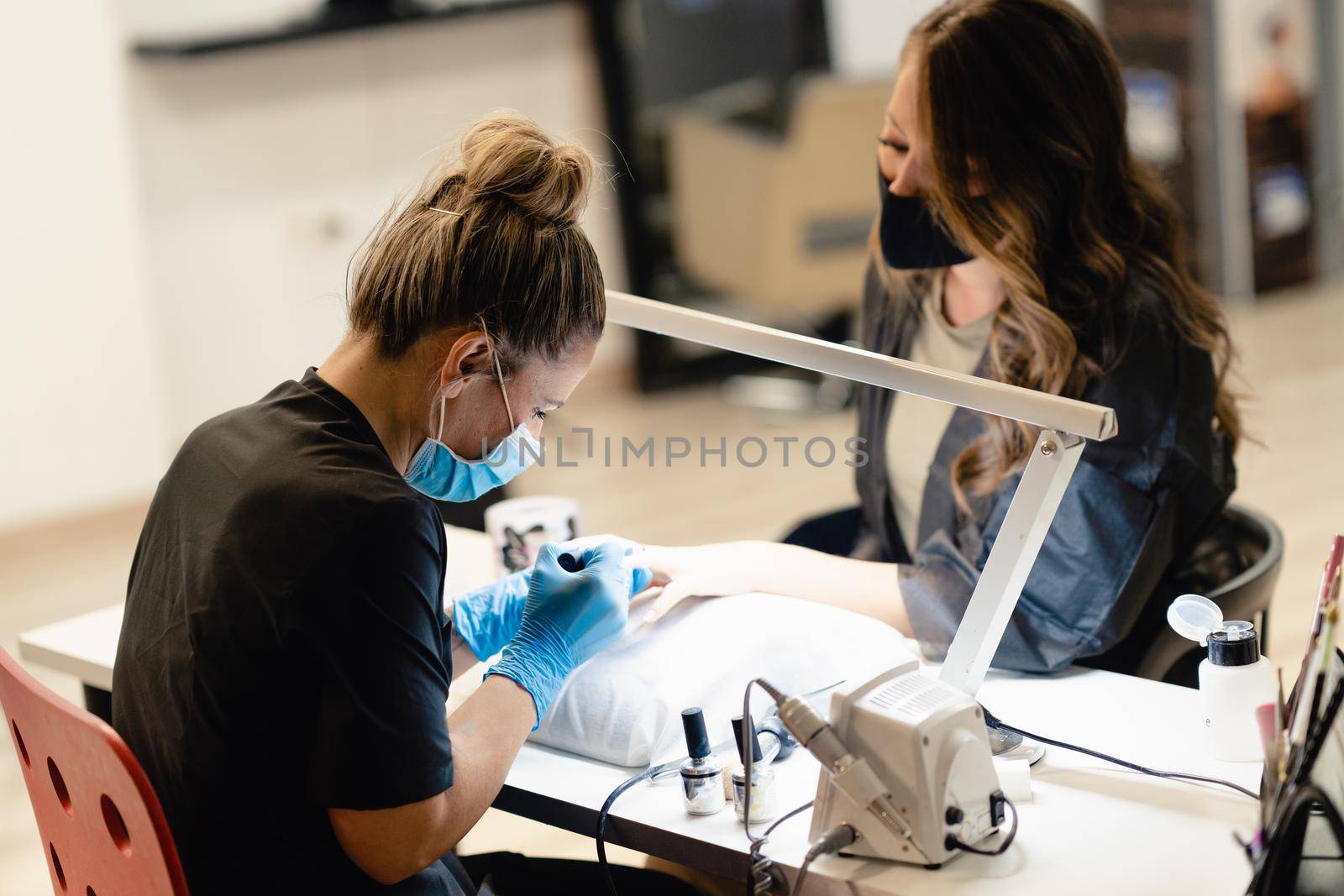 Manicurist paints nails with gel polish on clients nails. Manicure service.