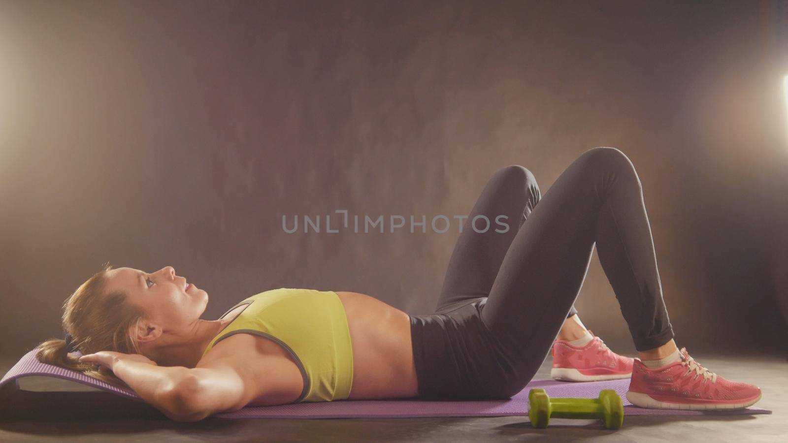 Practicing fitness. Beautiful woman in sports clothing training bodybuilding in studio, close up