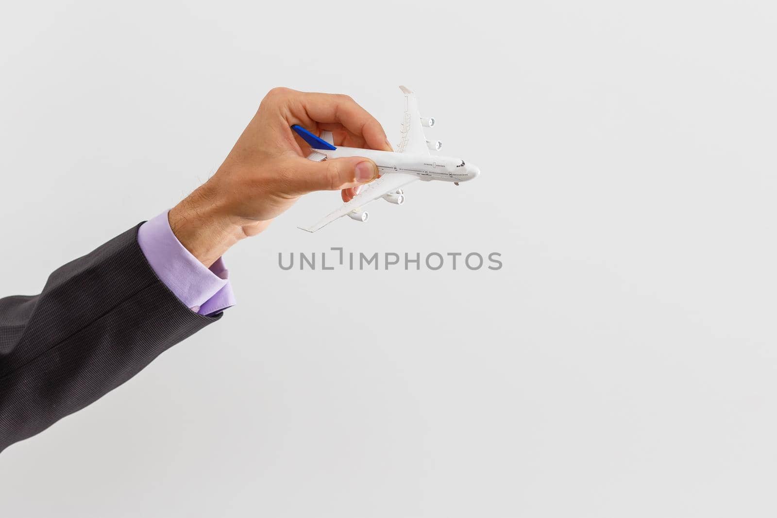 Adult businessman in suit holding a plane isolated on white
