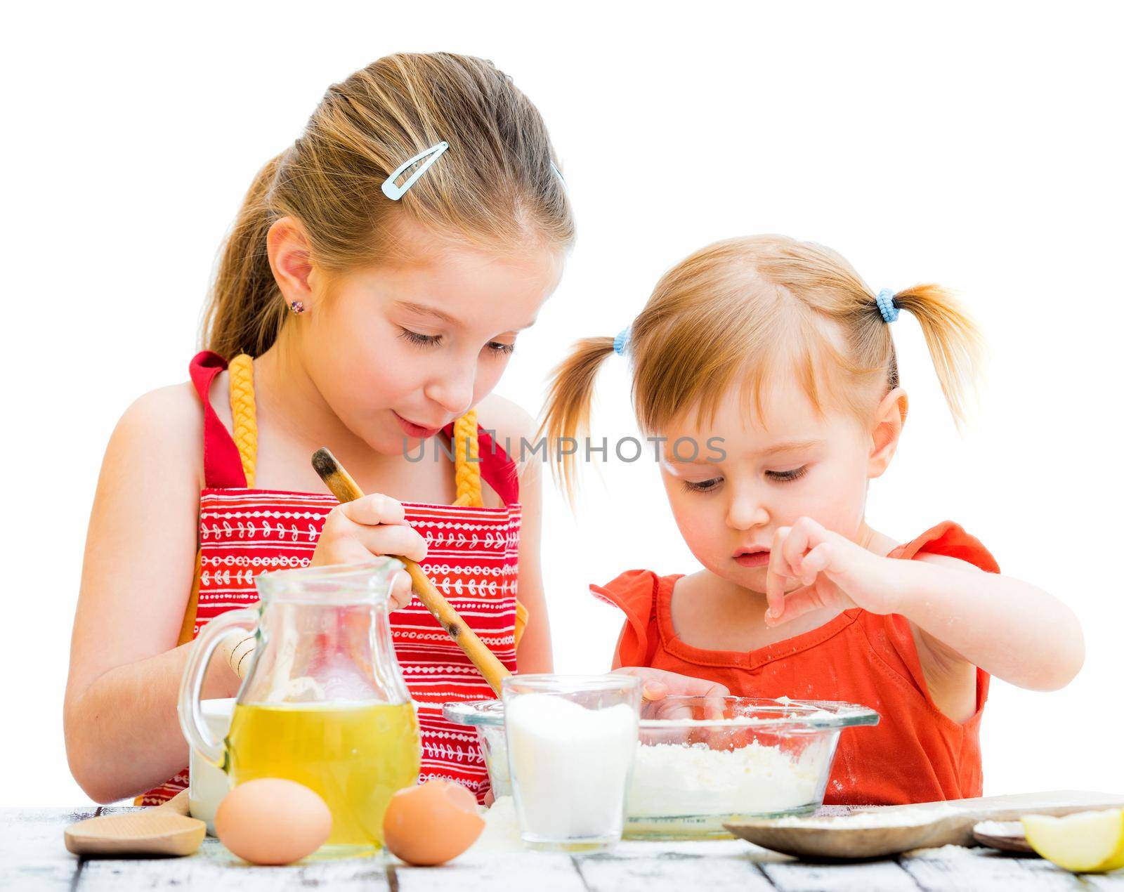 two cute little sisters cooking, on a white background