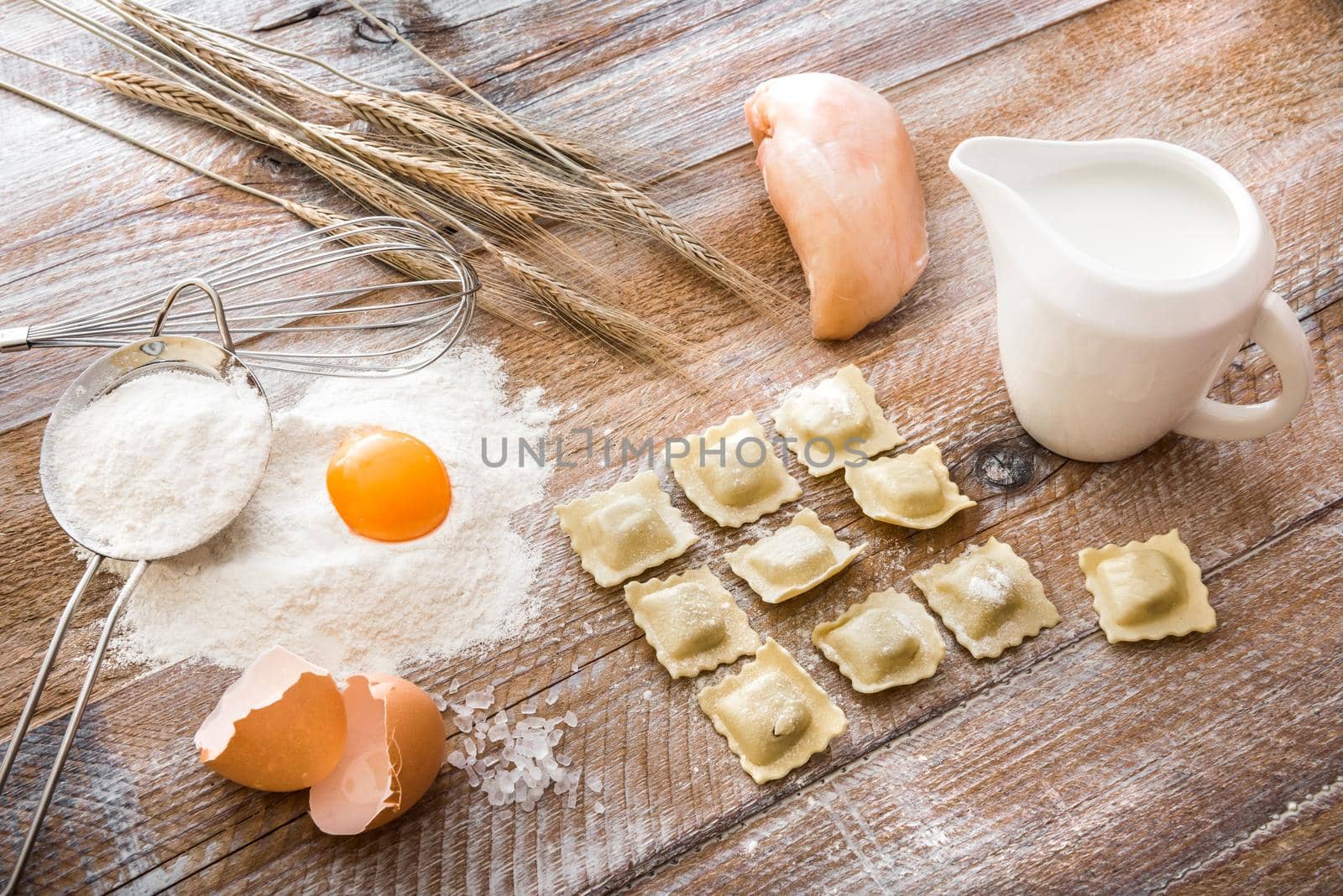 Tortellini on wooden board with chicken and other products