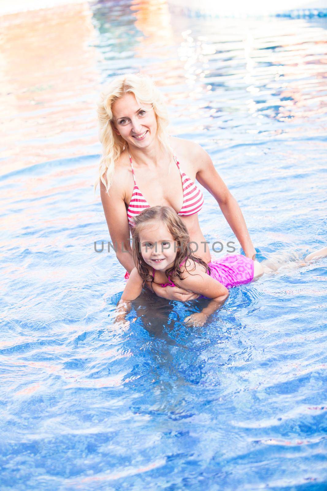 Mother is teaching her daughter to swim at the swimming pool