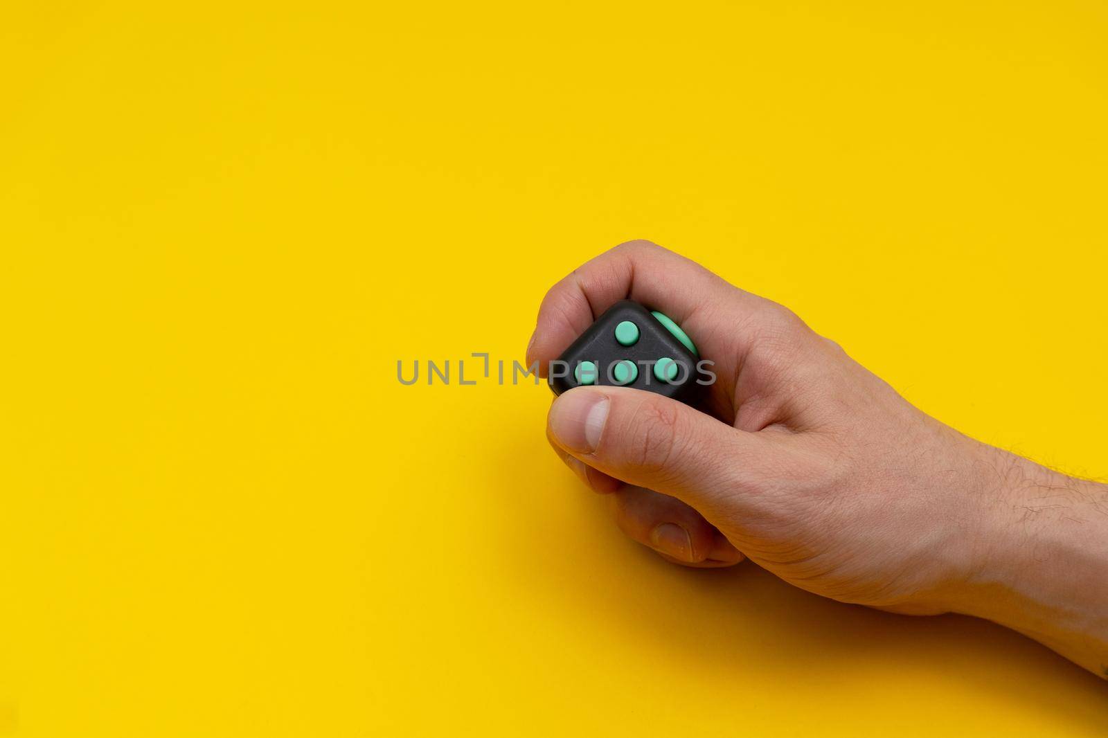 Antistress fidget in mans right hand on yellow background by uveita