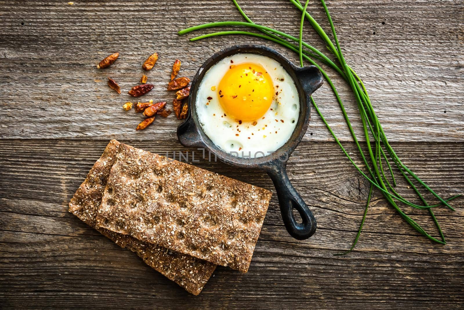 breakfast with fried egg, wheat bread and thyme on wooden background