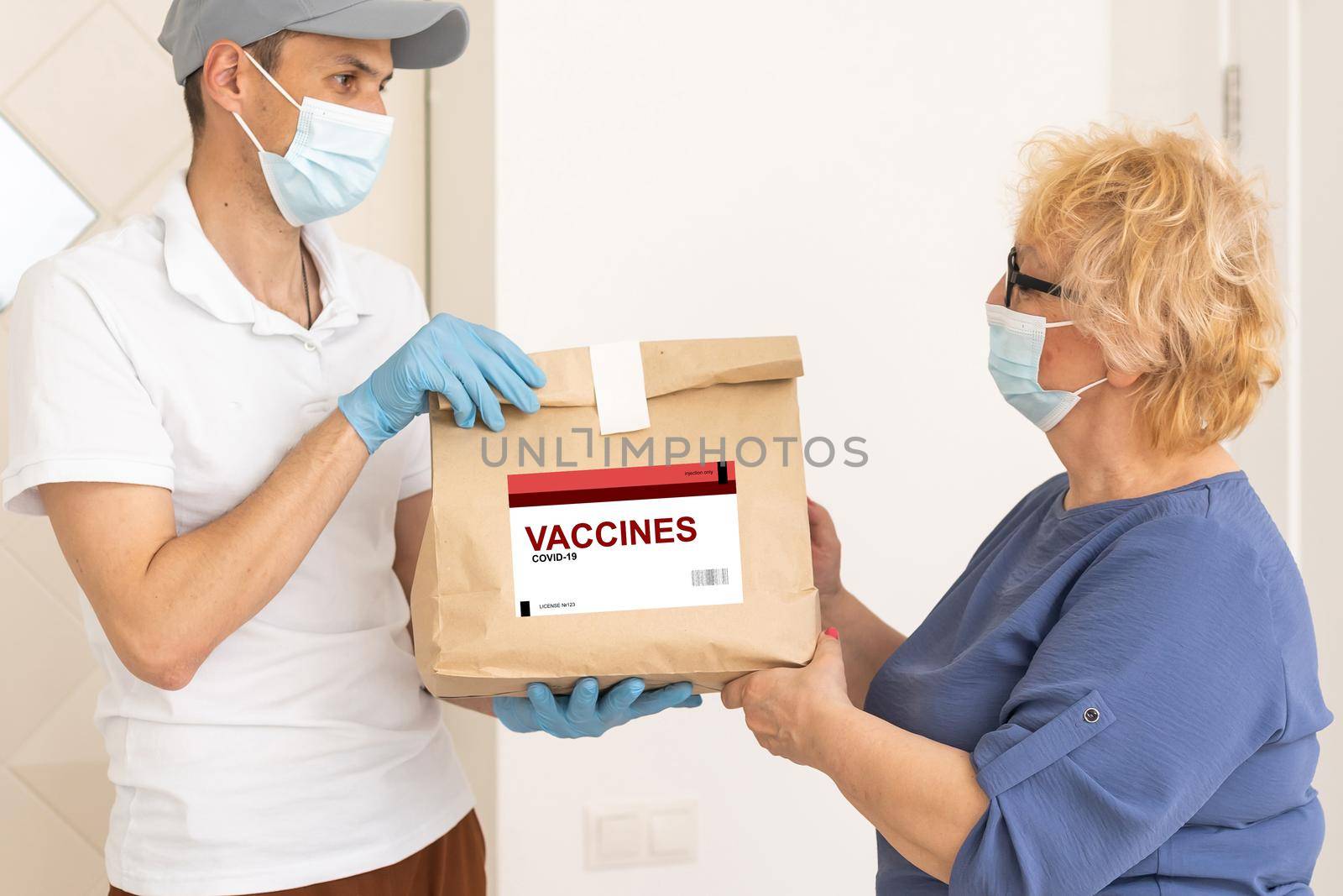 Contactless delivery during COVID-19 pandemic lockdown concept. Courier wearing mask and gloves deliver a parcel with medical equipment and to the customer.