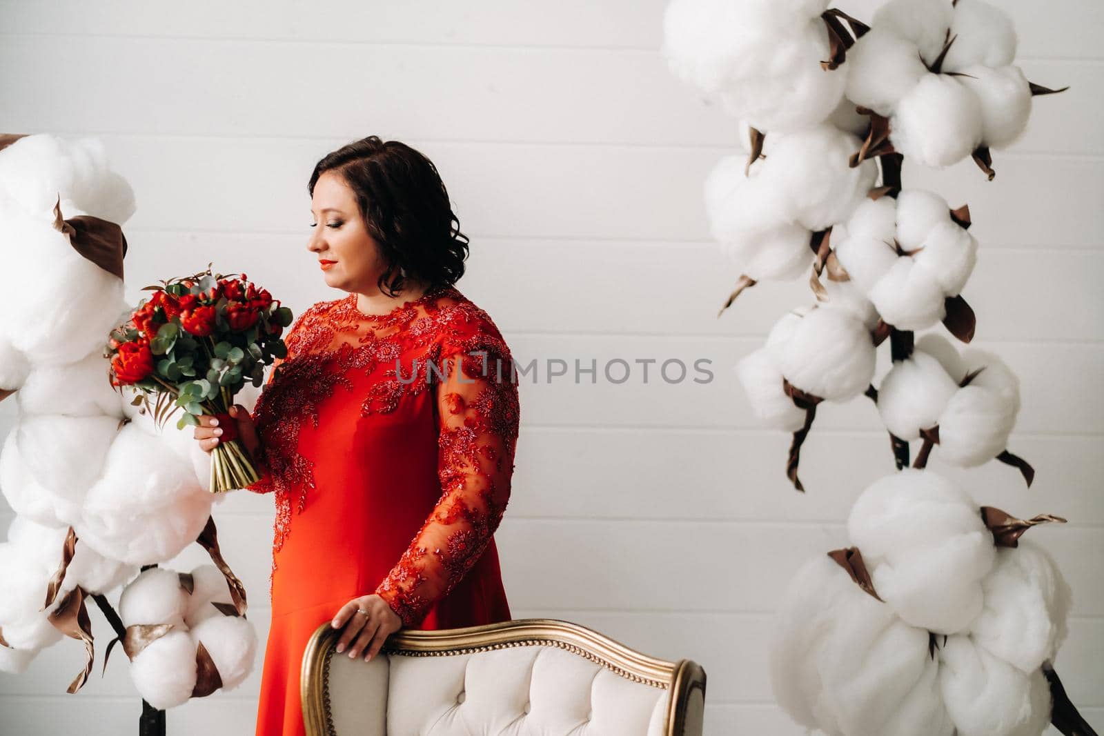 a woman in a red dress stands and holds a bouquet of red roses and strawberries in the interior. by Lobachad