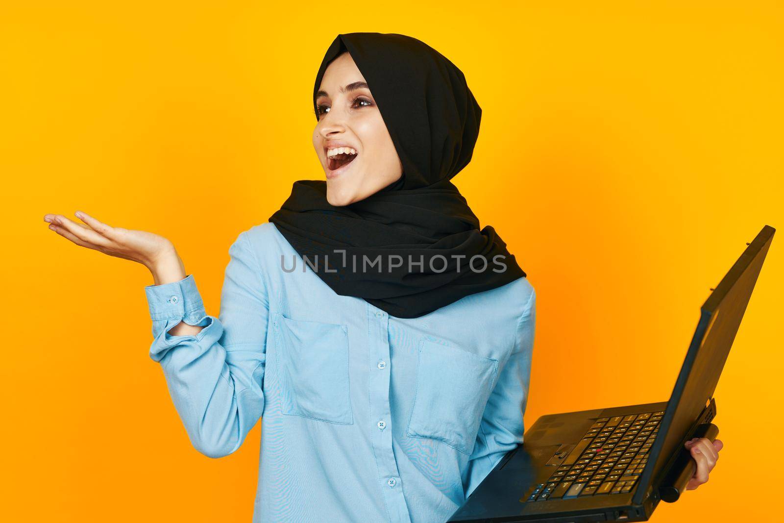 woman in black hijab with laptop in hands technology emotions studio lifestyle. High quality photo