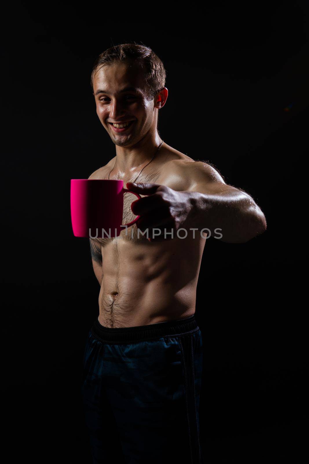 Man on black background keeps dumbbells pumped up in fitness muscle sexy body exercise powerful, male pectoral. Attractive sportive one fit In the athlete's pink cup he smiles by 89167702191