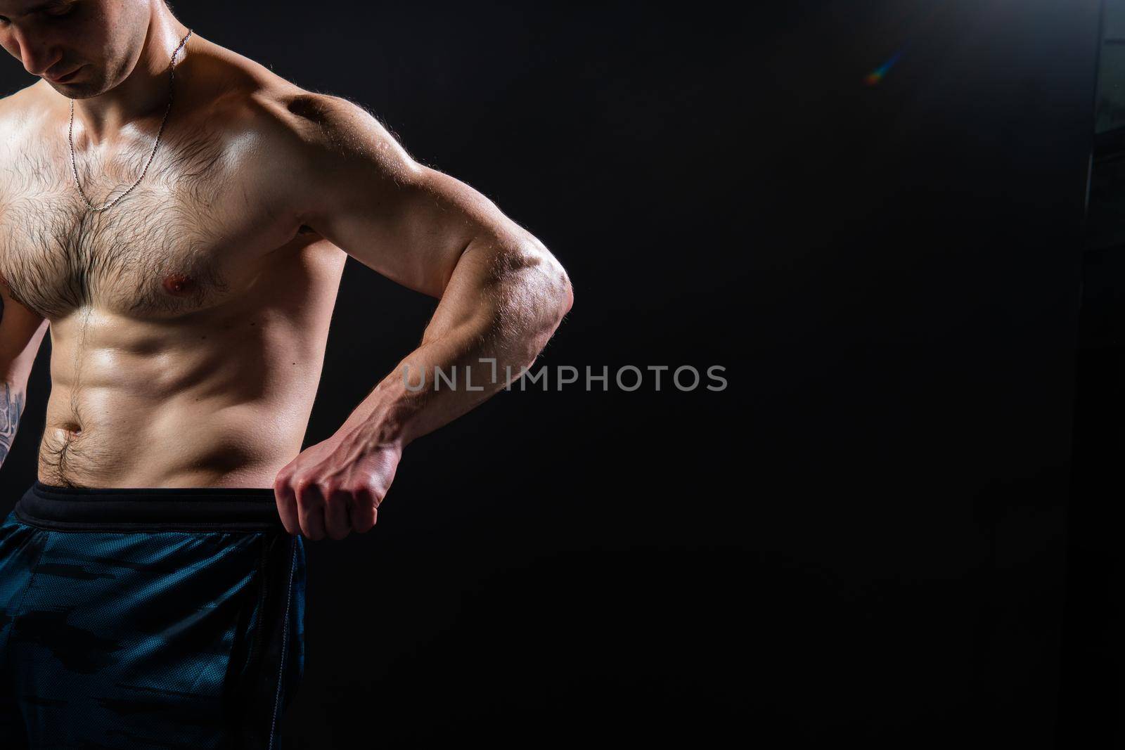 Man on black background keeps dumbbells pumped up in fitness muscle chest sport, arm weight strong lifting powerful, person Attractive sportive power, human fit Look at the press and measures the size of pants for weight loss, lovely press