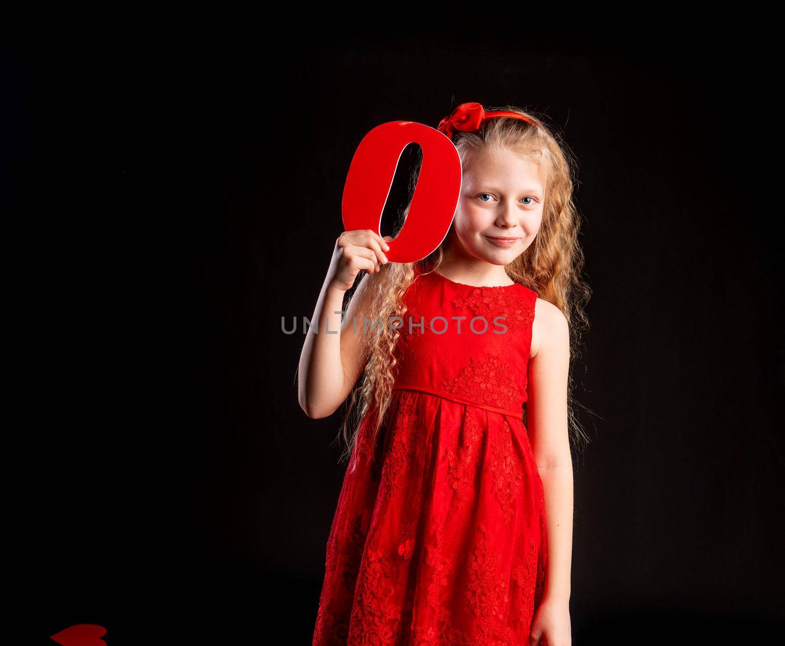 O holds a child holding in his hand the letter LOVE Valentine symbol, board, on the floor hearts of romance space. formula art. emotion feeling, gift in red girl dress, barefoot