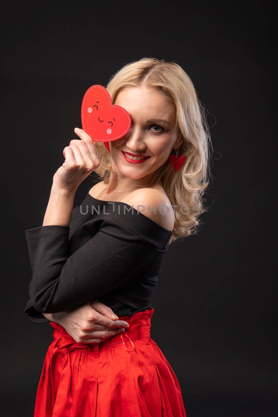 Girl holds a heart at eye level Valentine's day, heart Valentine's day, on the floor hearts romance. the formula of art. day feeling, hearts in red dress girl, barefoot