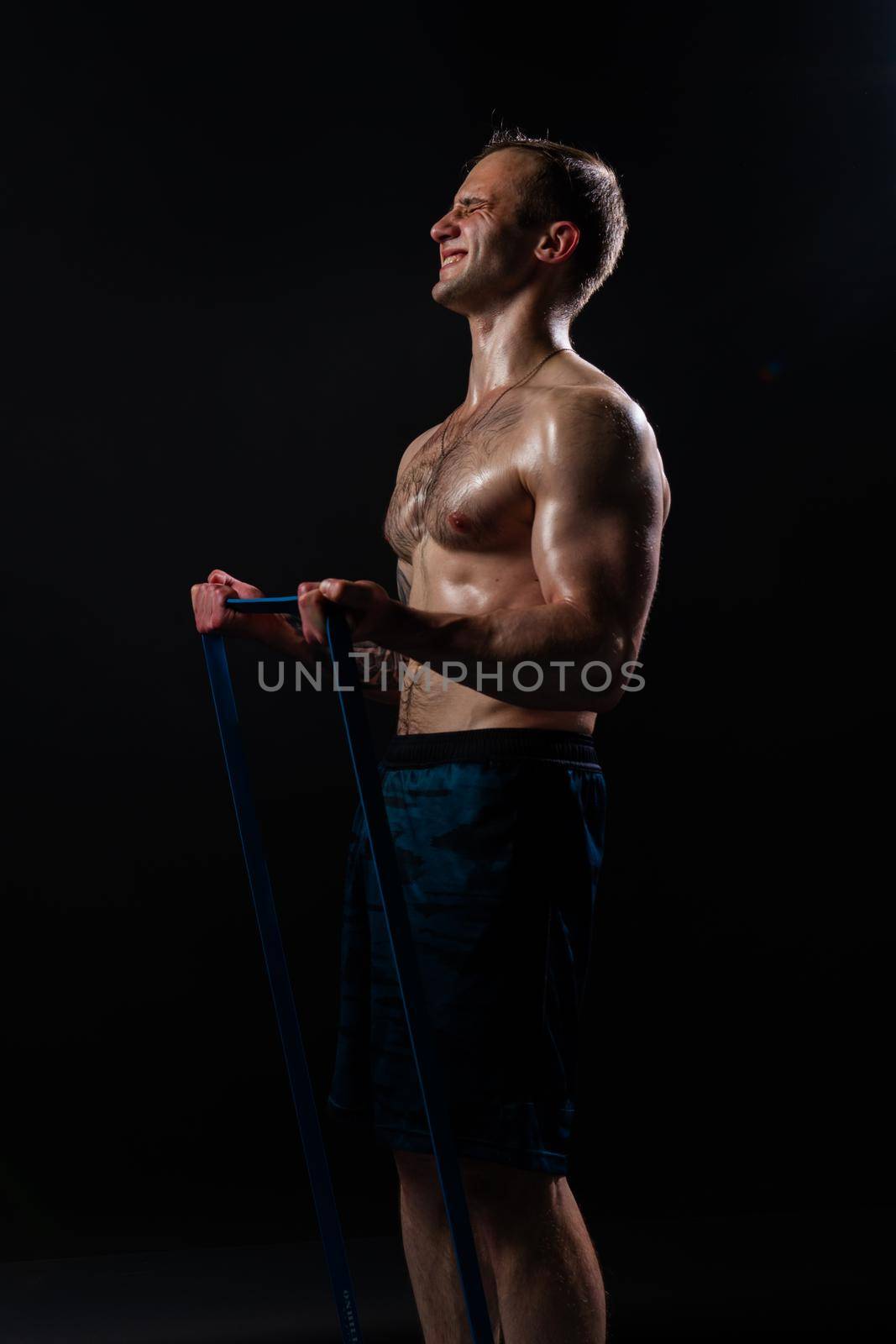 Man on black background keeps dumbbells pumped up in fitness bodybuilding sport, muscular exercise hand, Young skin power, guy fit With a ribbon in hand, the fitness gum is black