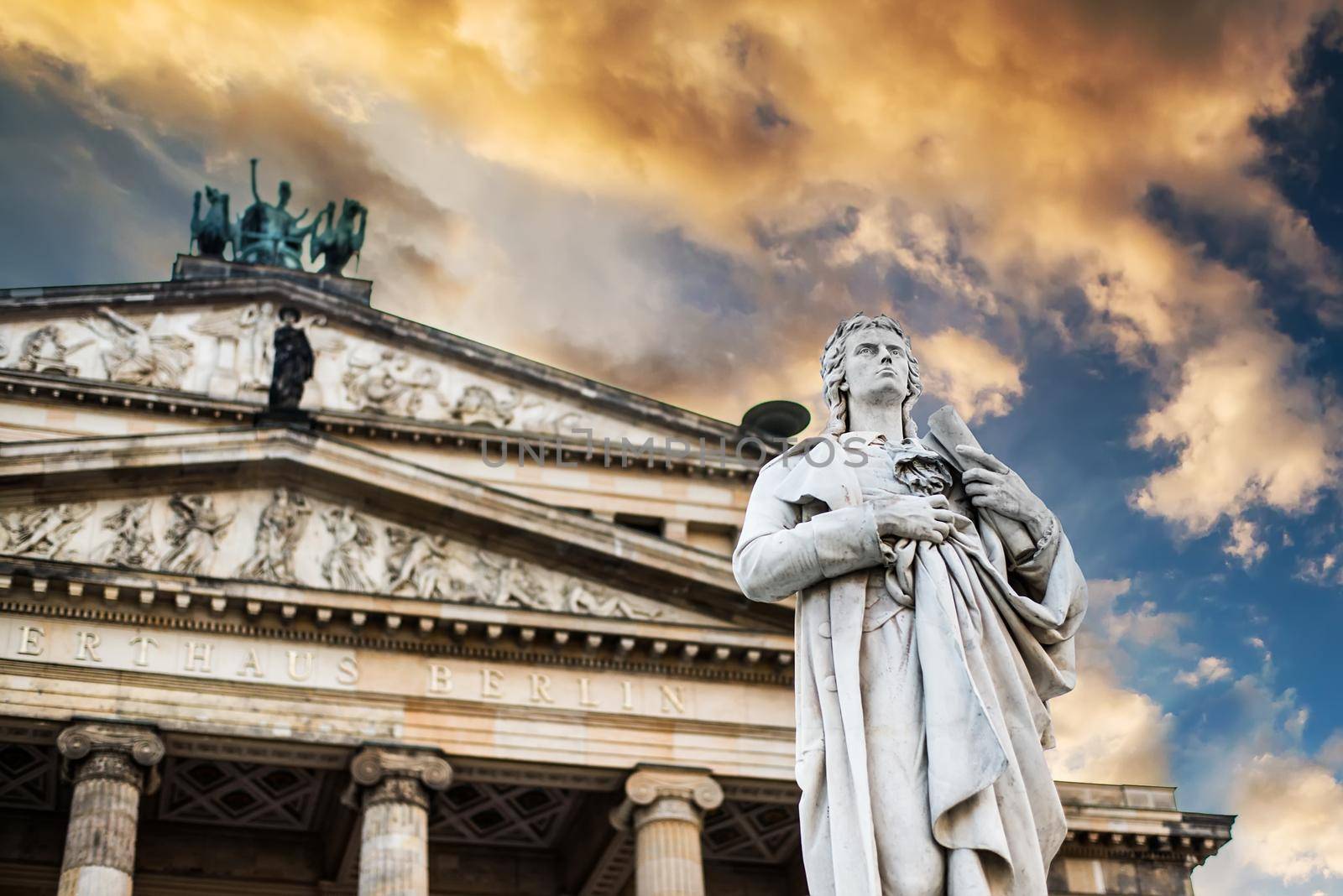 Beautiful squares in Berlin, the Gendarmenmarkt, marble statue of German poet Friedrich Schiller at sunset