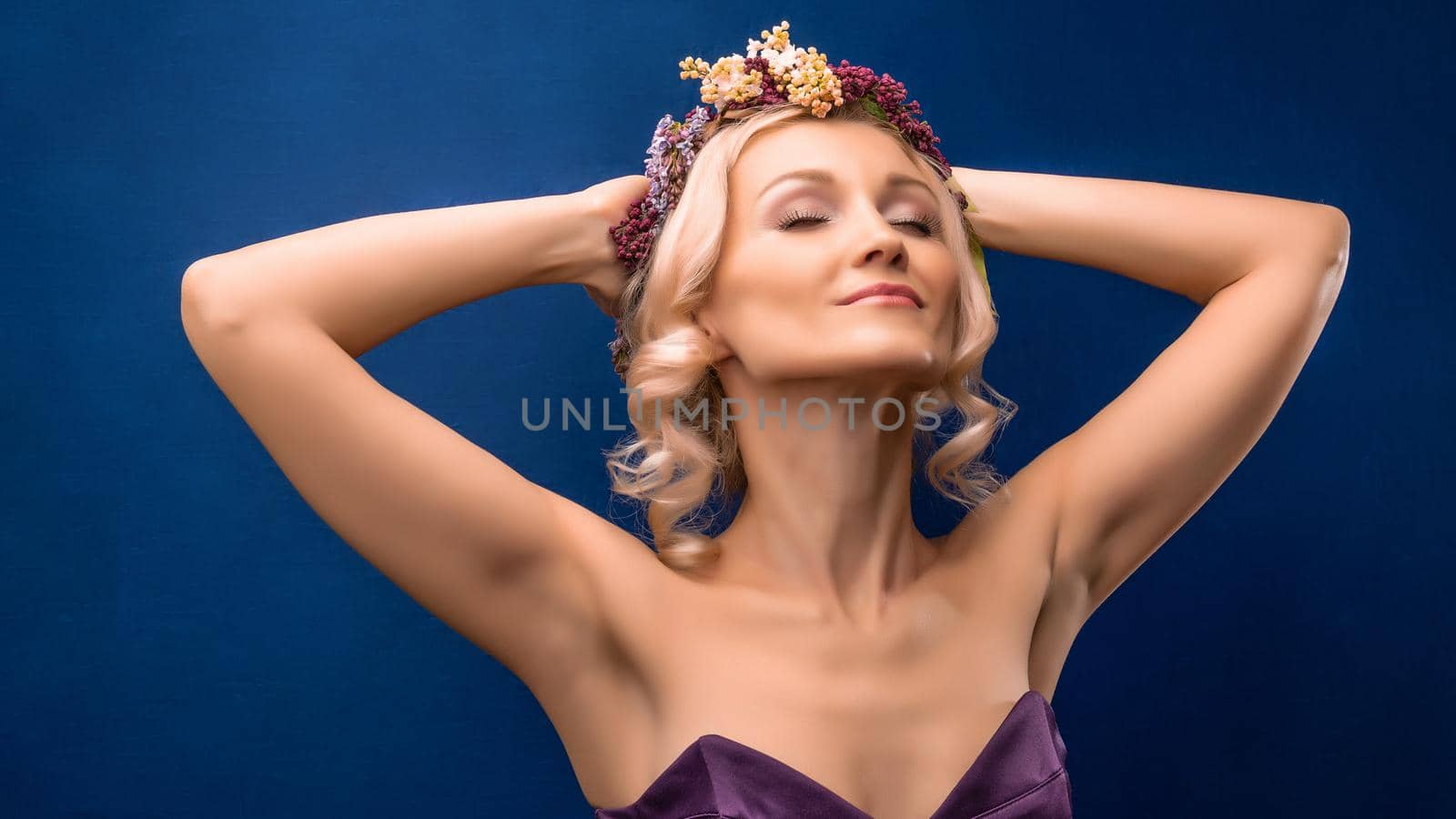 Lucky, young, wonderful, in a lilac wreath with white skin overjoyed on a blue background, with bright daylight