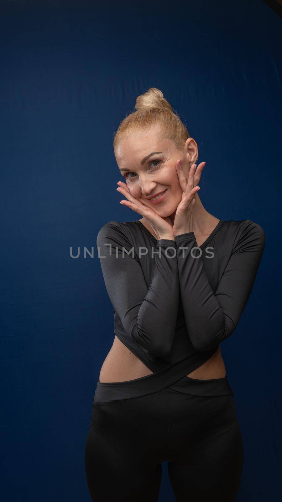 Overjoyed, a young, exhausted woman poses for the camera, an incomparable tuxedo dress with a beautiful appearance on a blue day background. Make up