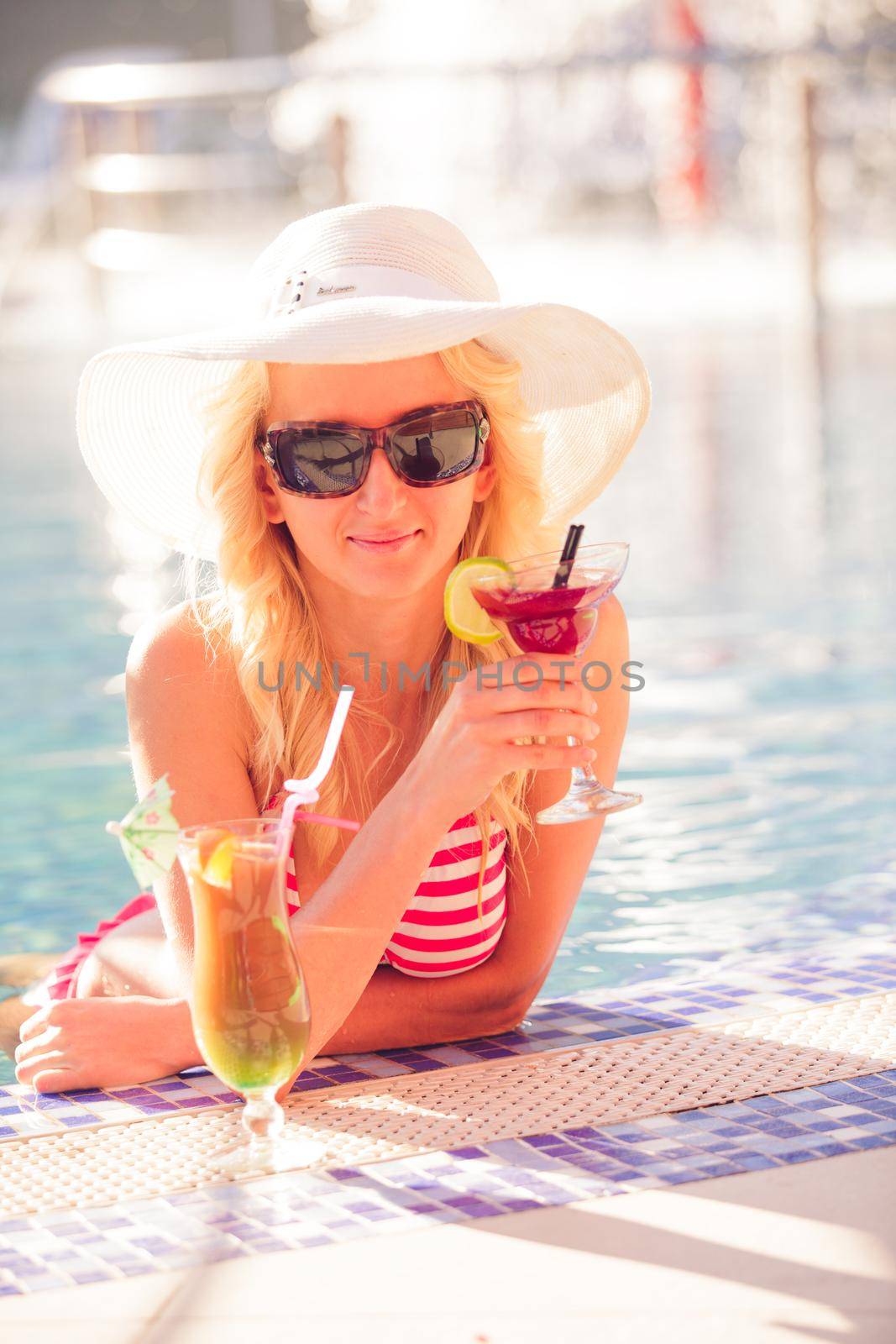 Blonde woman in hat at the swimming pool