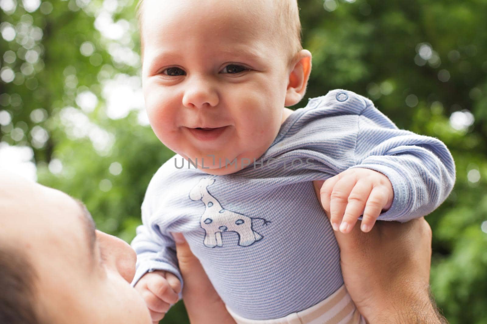 Father plays with son in a park. Flying baby