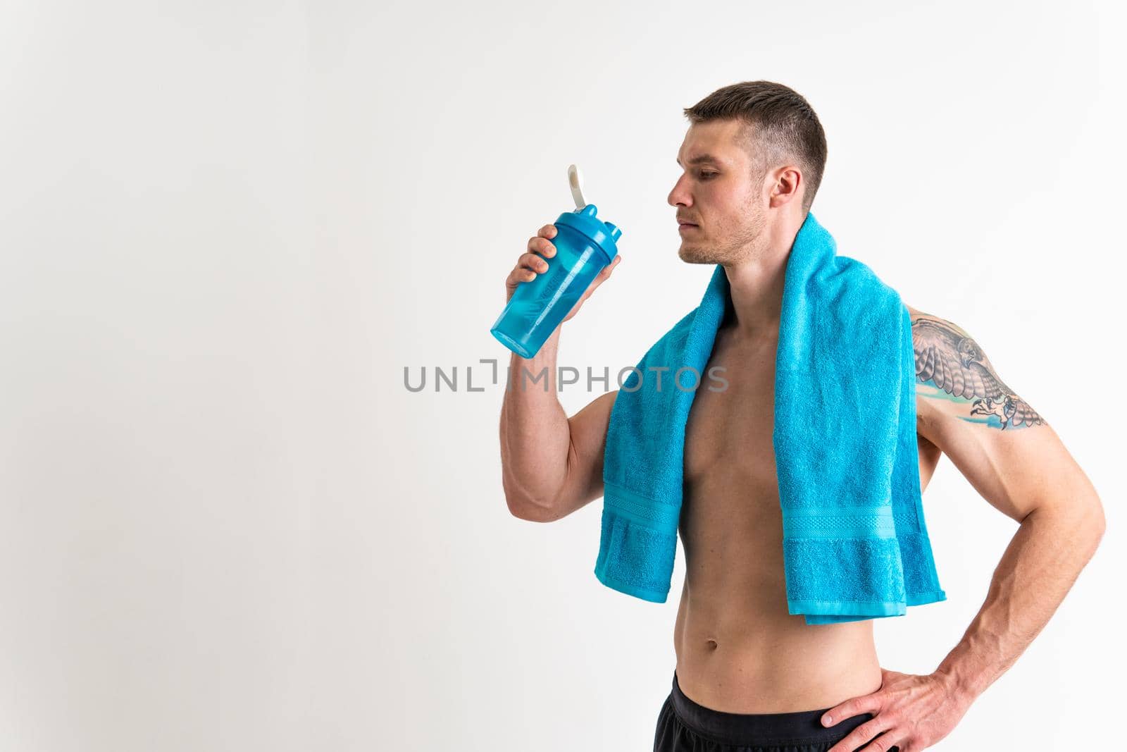 Male drink-water fitness is pumped with a towel on a white background isolated fit muscular lifestyle, water exercise adult athletic. Strength thirsty one muscle by 89167702191
