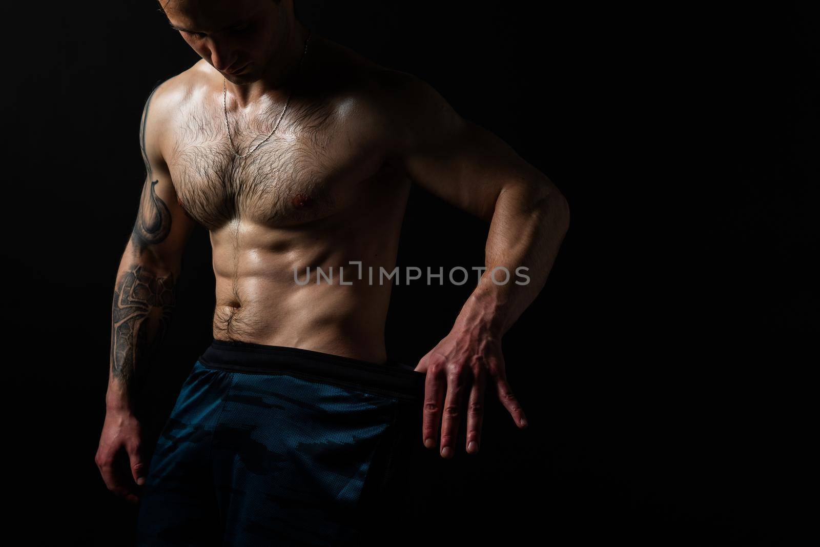 Man on black background keeps dumbbells pumped up in fitness bodybuilding chest black, training exercise hold shirtless lifestyle. Young handsome people fit Look at the press and measures the size of pants for weight loss, lovely press by 89167702191