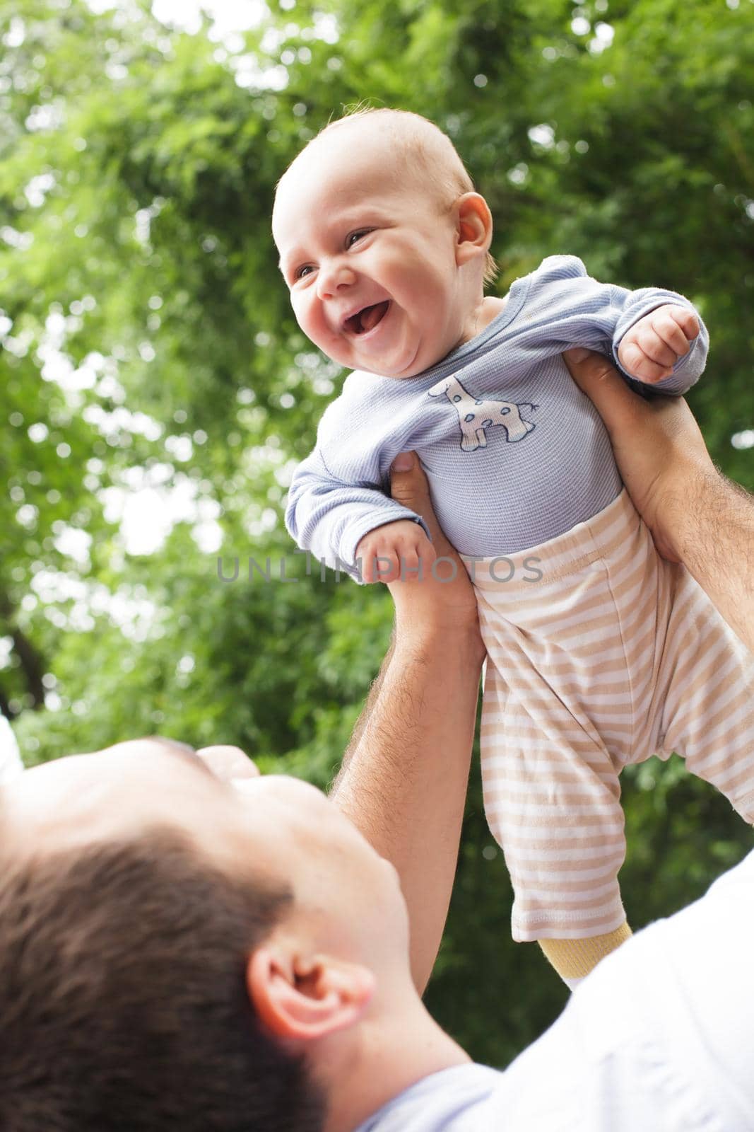 Father plays with son in a park. Flying baby