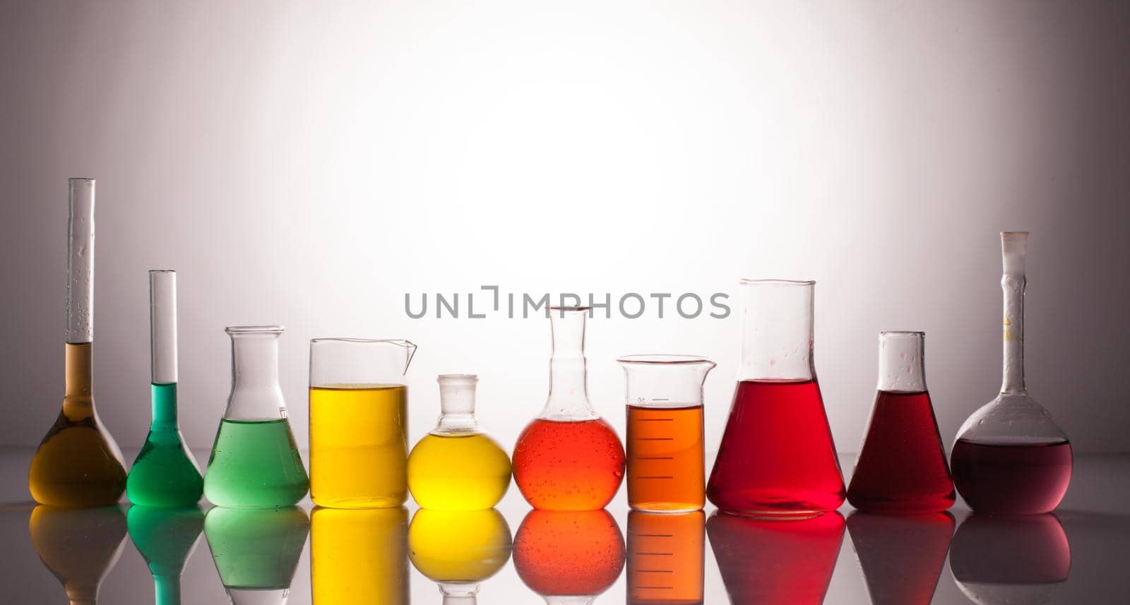 Laboratory glass with rainbow color liquids, chemistry still life