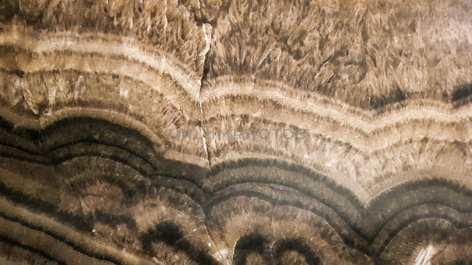 The surface of Sandstone with wavy brown veins. Sulphide agate texture. Wide image of brown natural stone texture Sphalerite. Beautiful wavy pattern of cut of Schalenblende stone close-up.