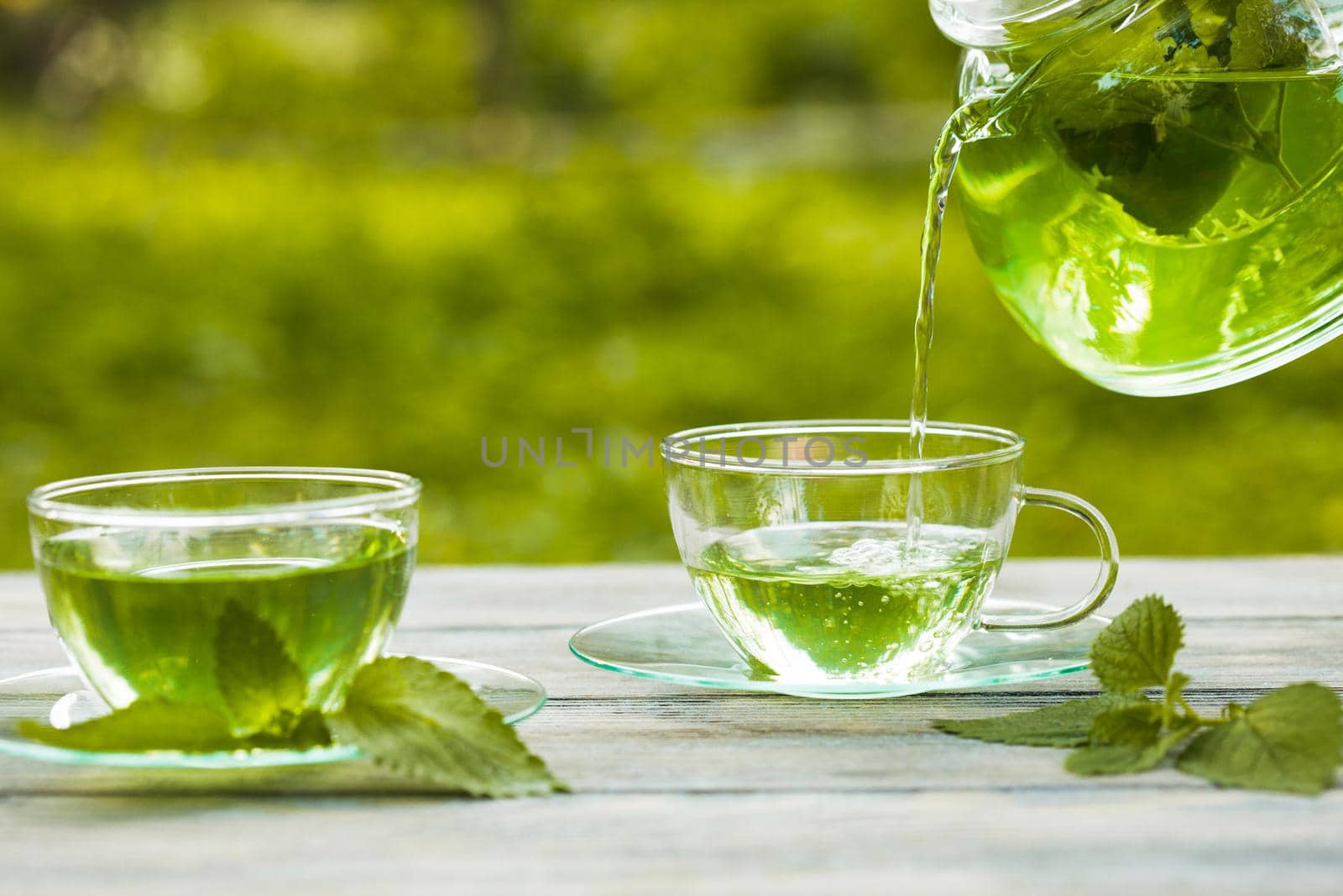 Herbal tea with melissa in a glass cup and teapot