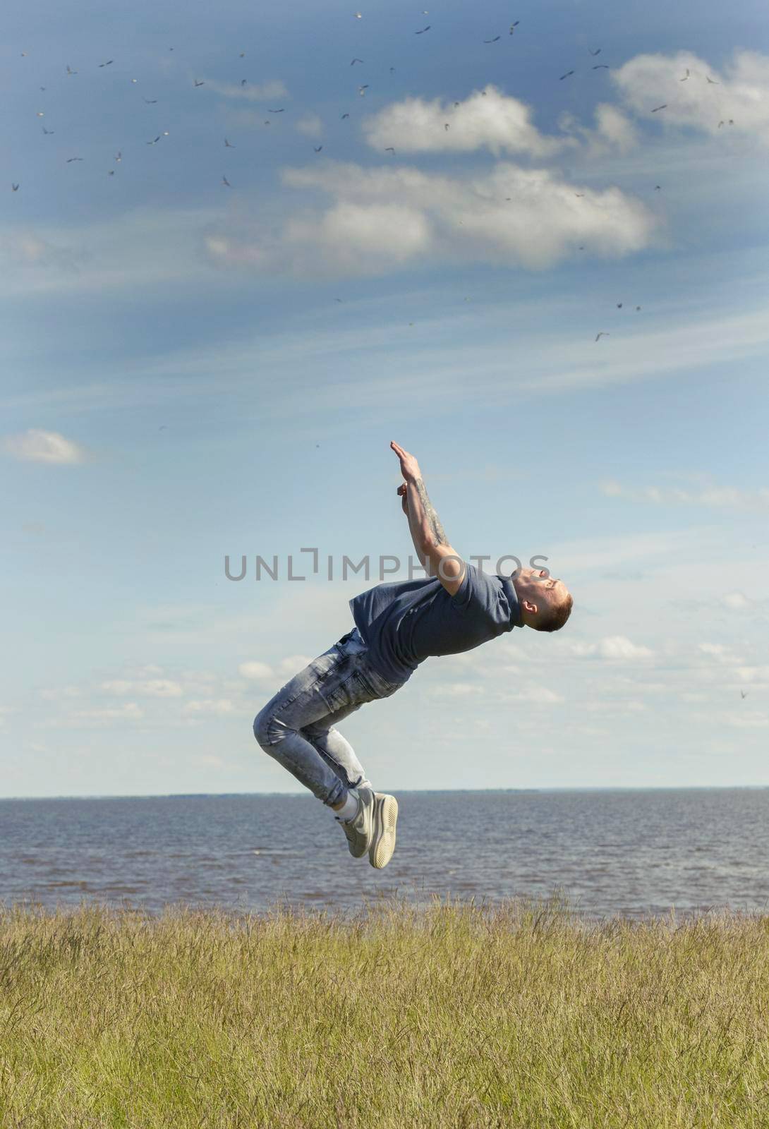 Young man performing flips on the hill over the river at summer sunny day, close up