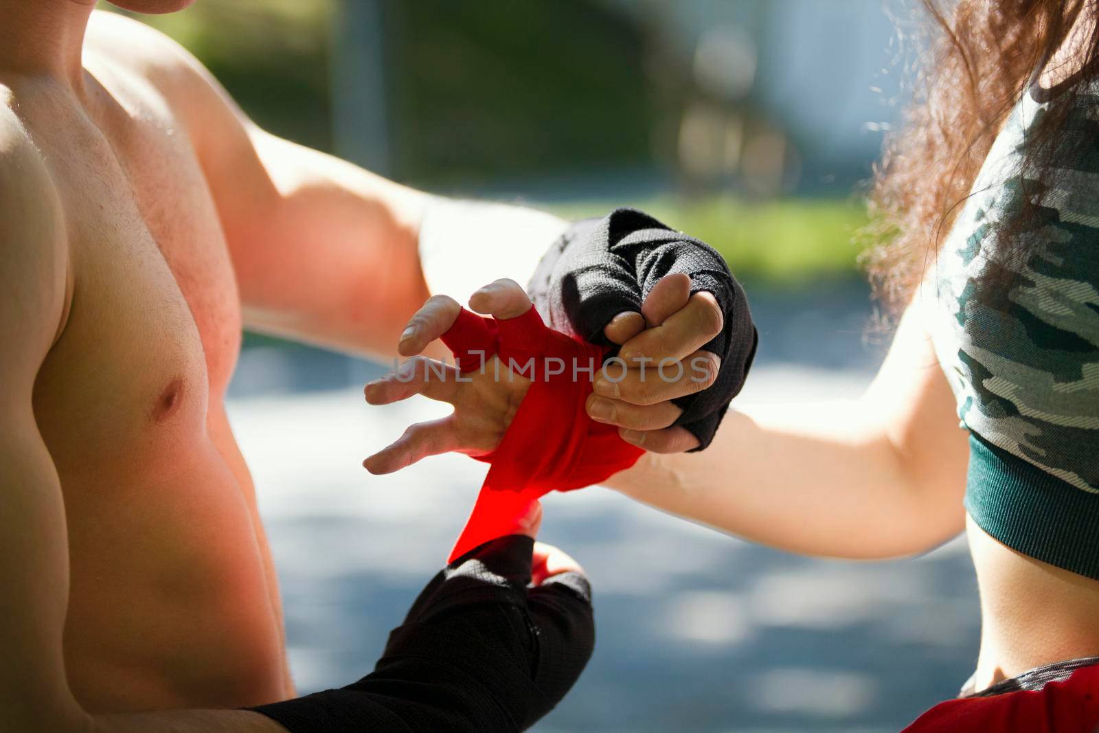 Hands of young man and woman wrapping hands with bandages for workout in summer day, horizontal