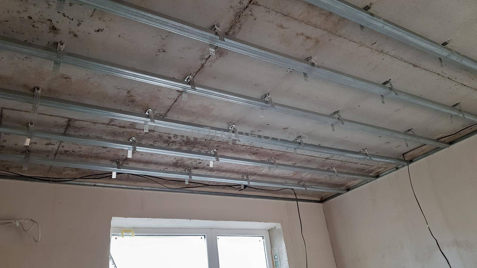 False ceiling design, before installing drywall. Plasterboard ceiling of a house at a construction site, installation of a false ceiling in a square room.
