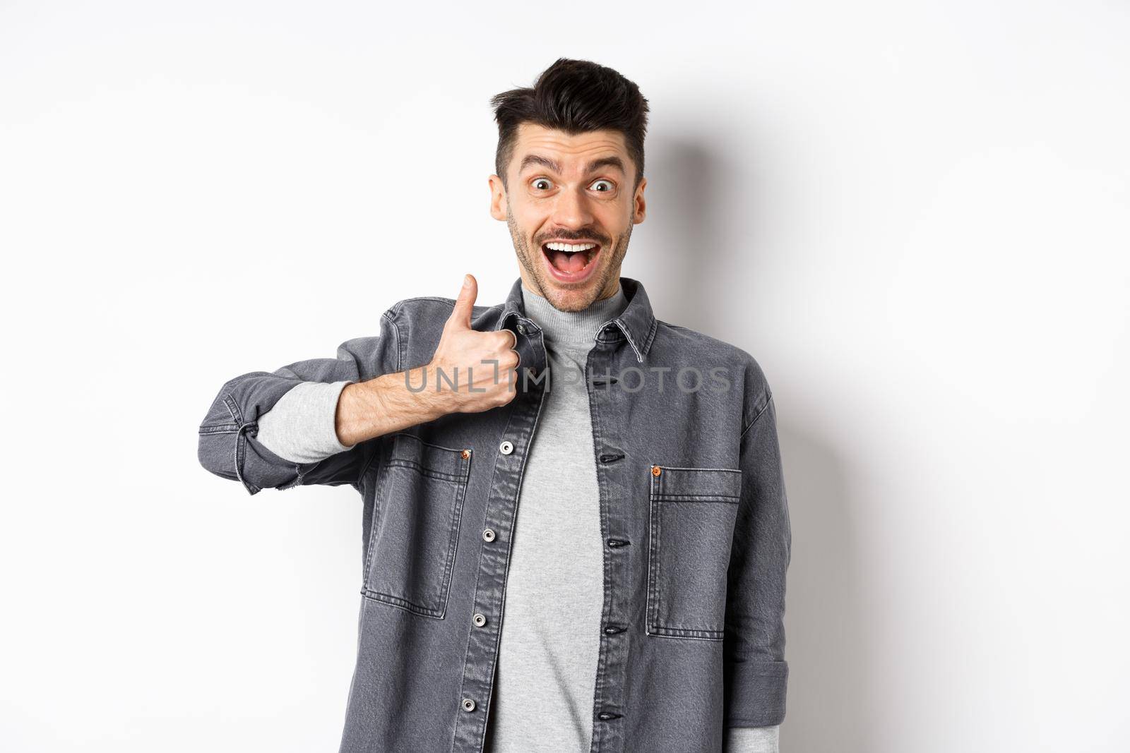 Well done, very good. Excited handsome guy praising nice work, showing thumb up and smiling happy, approve awesome choice, standing on white background.