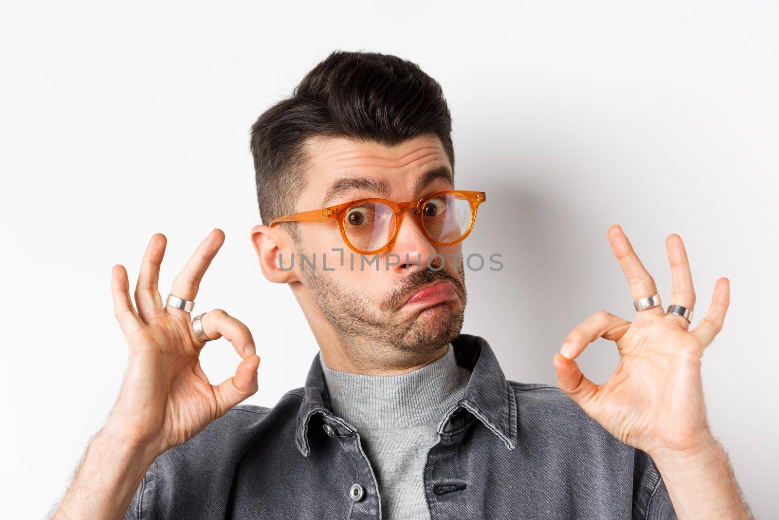 Not bad. Impressed man in stylish glasses showing okay signs and nod in approval, prase good thing, making compliment, standing on white background.