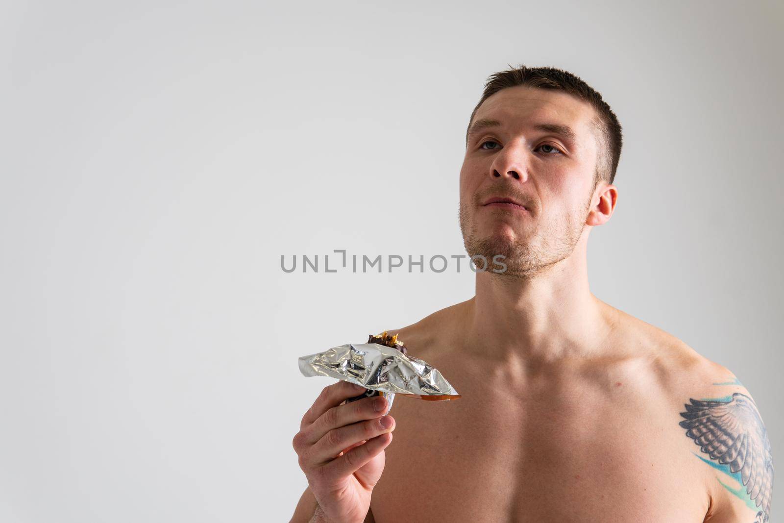 Man eats protein bar on white background isolated protein energy food, holding athlete caucasian, delicious calorie. break granola, smile female by 89167702191