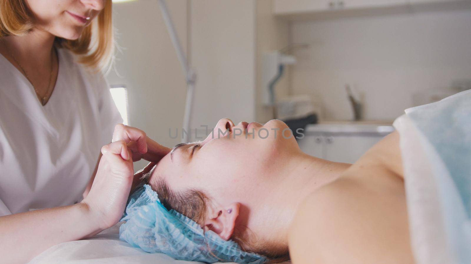 Woman doctor performes cosmetic procedure - mask facial massage at spa salon skincare, close up