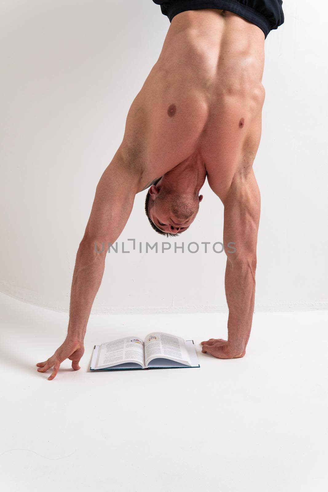 Bodybuilder reads the book on a white background isolated at the bottom of his head on his hands bodybuilder book muscular, muscle strong white background shirtless, intellectual fit. Isolated manager holding, beach tan