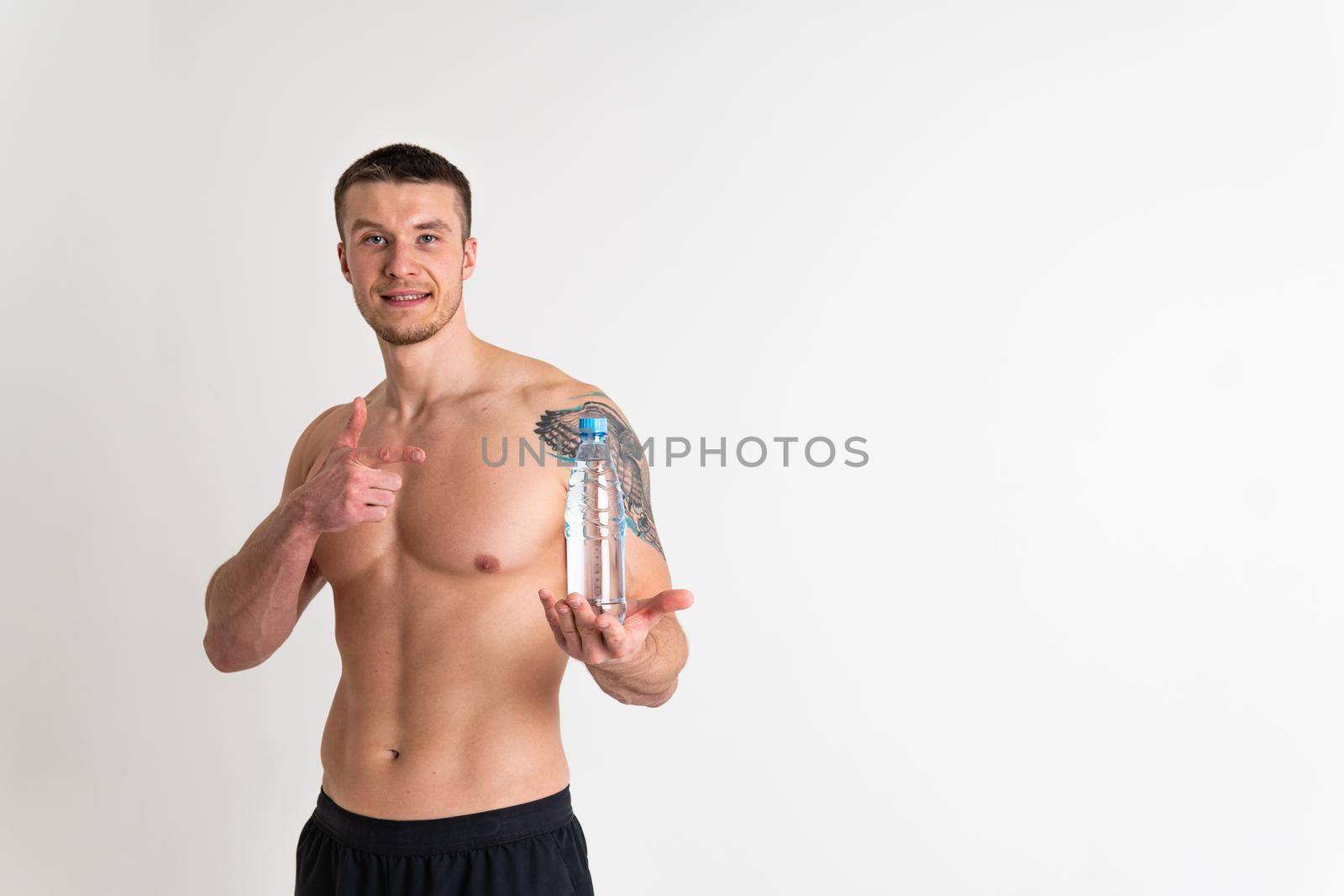 Male drink-water fitness is pumped with a towel on a white background isolated fitness workout body, exercise gym man break cardio. Bodybuilding active, powerful one muscle