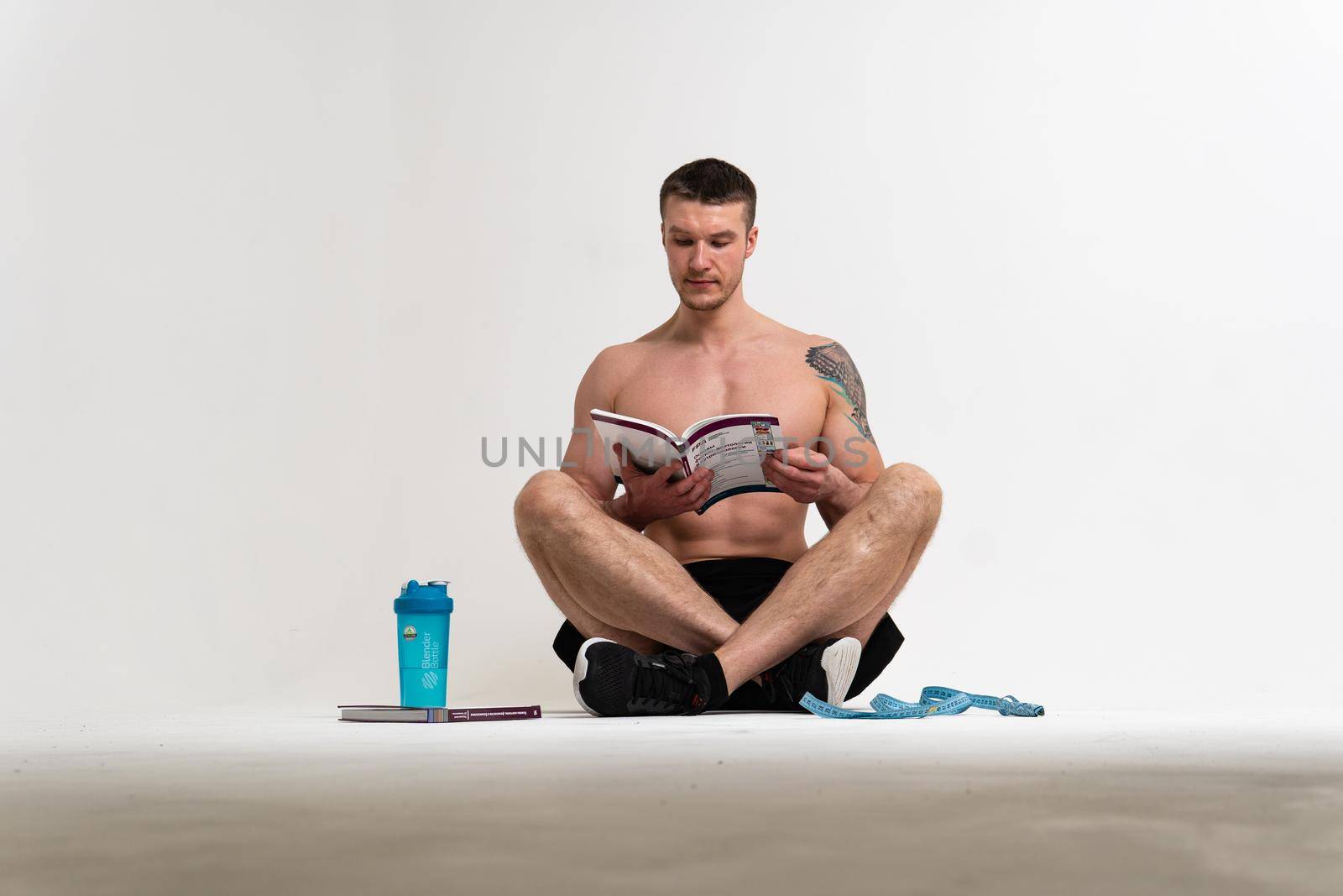 Bodybuilder reads the book on a white background isolated at the bottom of his head on his hands young muscle strong bodybuilding background healthy, happy fit. holding, beach tan