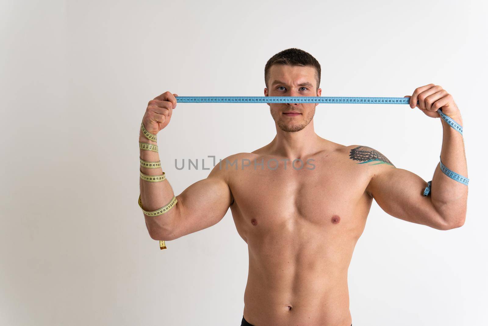 A man measures the waist of a metre and poses against a white background isolated young waist, girl abdomen exercise weight, white. Measure nutrition studio, caucasian sport attractive tape